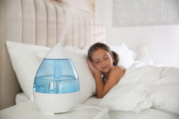 Cute little girl sleeping in bedroom with modern air humidifier - obrazy, fototapety, plakaty
