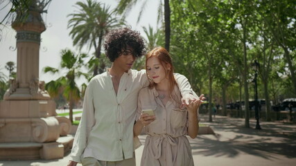 Fototapeta premium Romantic couple walking with mobile around city. Focused couple holding hands