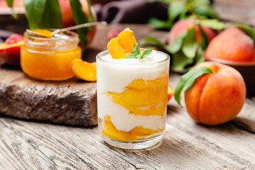 Peach fruit dessert in glass cup on rustic wooden table with fresh peach fruit, peach jam. Homemade...