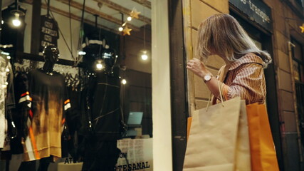Tourist woman looking in shop windows. Closeup girl walking with shopping bags