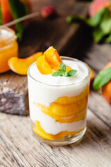 Peach fruit dessert in glass cup on wooden table. Homemade dessert with fruits. Fruit salad with yogurt or sour cream.