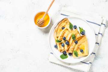 Crepes with blueberries at white table.
