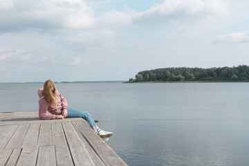  girl  on the pier and looks into the distance. Mental health, sadness, loneliness. Meditation, taking care of herself stayhome, wellness during the lockdown quarantine coronanavirus covid19