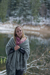 portrait of a woportrait of a woman in winter. Girl near the lake in winter. A young woman is wrapped in a plaid.
