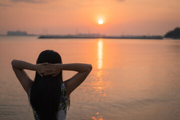 Woman looking at the sunset on the beach.