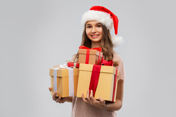christmas, holidays and people concept - happy smiling teenage girl in santa helper hat holding gift box over grey background