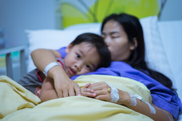 Woman patients lying on bed in hospital. Hands with saline solution. Her hand is held by her son's hand for encouragement. She hugged and kissed her son.