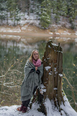 Fototapeta na wymiar portrait of a woman in winter. Girl near the lake in winter. A young woman is wrapped in a plaid. 
