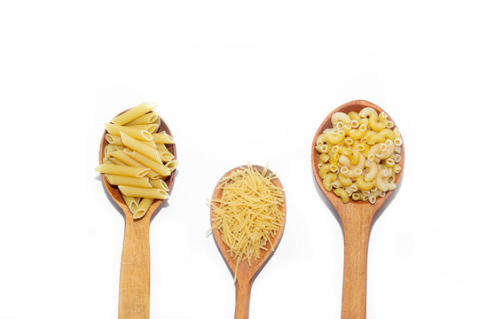 Macaroni several types in wooden spoons on a white background . Macaroni on wooden spoons . Macaroni on a white background. Article about the choice of pasta. Ingredients for the dish. Copy space . Is