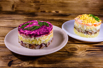 Traditional russian new year layered salads Mimosa and Herring under a fur coat (shuba) on wooden table