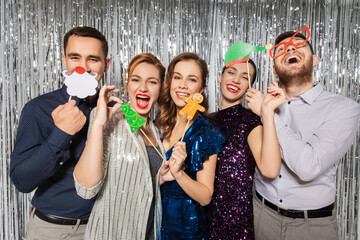 celebration, christmas and holiday concept - happy friends posing with party props