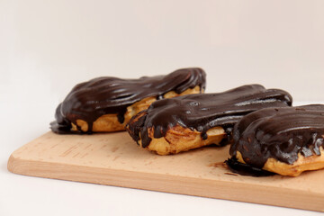 Chocolate eclair on wooden desk food photography. Bekery, cake , choco, pie, confectionary, cream. Three fresh eclairs with chocolate