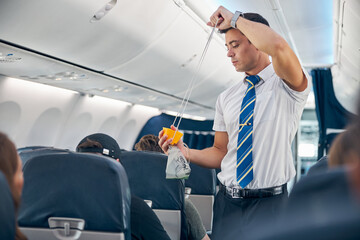Man with oxygen mask demonstrating safety procedure prior to passenger airplane flight © Svitlana