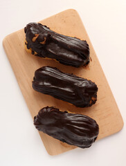 Chocolate eclair on wooden desk food photography. Bekery, cake , choco, pie, confectionary, cream. Three fresh eclairs with chocolate