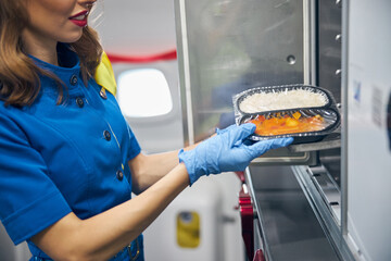 Stewardess serving food to the passengers at the kitchen of commercial airplane