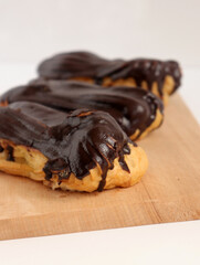 Chocolate eclair on wooden desk food photography. Bekery, cake , choco, pie, confectionary, cream. Three fresh eclairs with chocolate