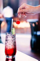 Sparkling cherry lime cocktail with ice cubes in clear glass on table