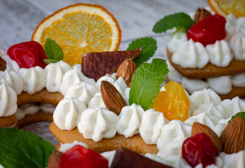 Creamy fruit cake with white filling with orange chips, dried fruits, decorated with mint
