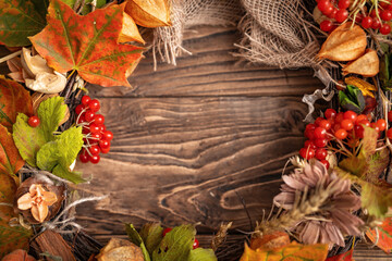 Naklejka na ściany i meble wreath of autumn leaves and natural materials on rustic wooden boards. Top view