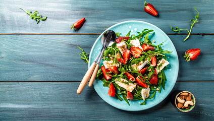 vegetarian healthy salad with arugula, strawberries and cheese brie, camembert. Healthy food diet food concept. recipe background