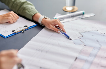 construction business, architecture and building concept - close up of architect with blueprint, clipboard and pen working at office