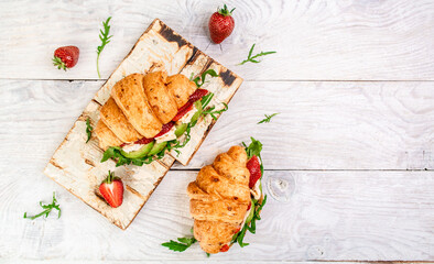 Breakfast, business lunch, sandwiches Croissant with strawberries and soft cheese with mold brie camembert on wooden background. banner menu recipe top view