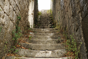      An ancient staircase between two walls in a dilapidated fortress.
