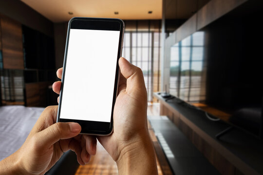 A man hand holding smart phone device in the bright office room interior..