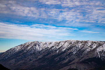 Naklejka na ściany i meble Blue sky and white clouds behind the snowy mountains.