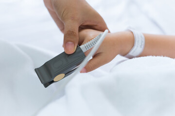 Hand of woman hold pulse oximeter for little Asian boy hand use to measure pulse rate and oxygen levels, patient with pulse oximeter on finger for monitoring in hospital. Healthcare medical concept.