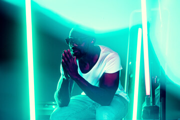 Rap star. Cinematic portrait of stylish young man in neon lighted room. Bright neoned colors....