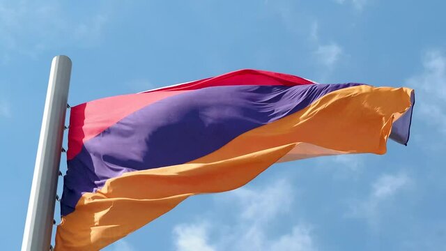 Armenian flag fluttering in the wind. National flag against a blue sky, high flagpole