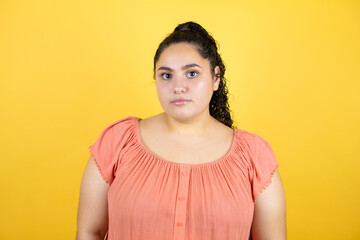 Obraz premium Young beautiful woman with curly hair over isolated yellow background serious looking at the camera