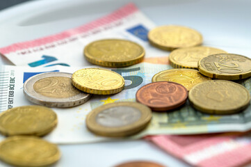 Close-up Of Coins And Currency Note On Plate. High Angle View. euro Money On White Plate. plate with coins and banknote. Toilet - Tip, church collection, rising costs, assets
