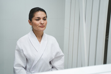 Woman dressed in a bathrobe standing in a bathroom