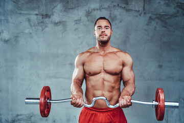 Sportsman with naked torso and strong hands keeping fit and lifting darbell in custom background.