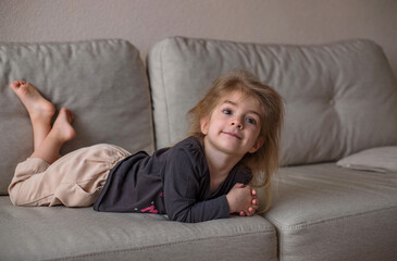 Quarantine. isolation, social distancing, stay home concept,Coronavirus pandemic world. Little cute girl have fun and lying on sofa at home in living room. life at home