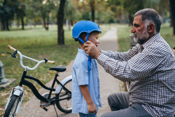 Plakat grandfather puts bicycle helmet to his grandson