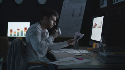 Obraz na płótnie Canvas Serious businessman working on computer in night office.