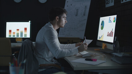 Professional businessman analyzing financial charts and data in night office