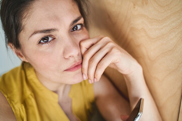Low-spirited lady holding a gadget in her hand