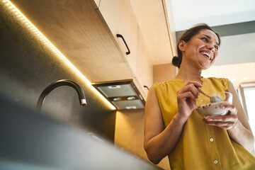 Merry woman dark-haired laughing heartily at breakfast