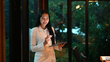 Portrait of bussinesswoman smiling to the camera while hands hold tablet and stylus pen at modern...