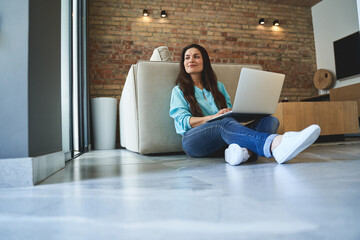 Pensive woman sitting cross-legged on the tile floor