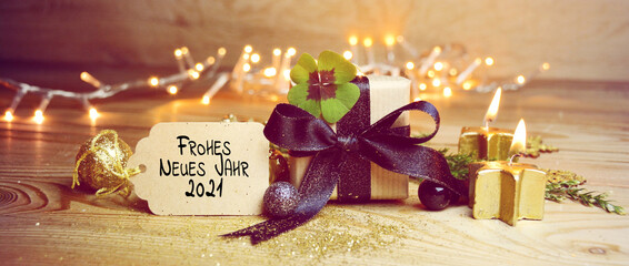 Frohe Neues Jahr 2021  means Happy New Year 2021 - New year congratulations - gift box with lucky clover and candles