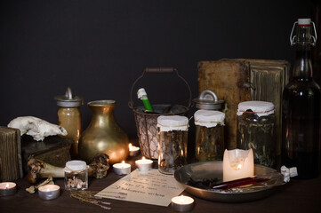 eerie witches' kitchen with lot of ingredients for a love potion and ancient gruesome jars dark with only candlelight for Halloween with copy space above