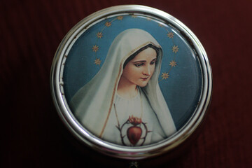 Portrait of Mother Virgin Mary on a cover of round metal rosary box. Pray rosary devotion concept....