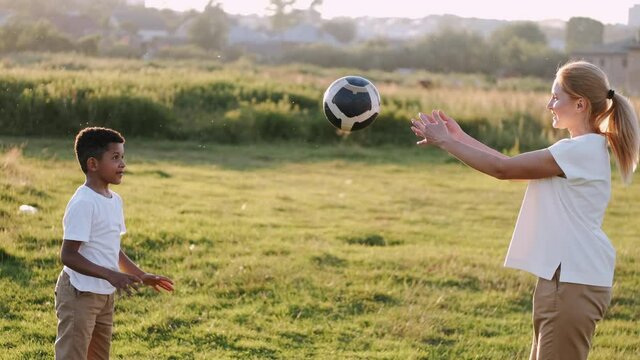 Image if happy family. Mother and son are playing with a ball in a summer field.