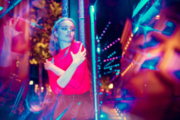 Moody. Cinematic portrait of stylish young woman in neon lighted room. Bright neoned colors. Caucasian model, musician outdoors. Youth culture in party, festival style and music concept.