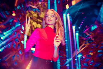 Evening mood. Cinematic portrait of stylish young woman in neon lighted room. Bright neoned colors....